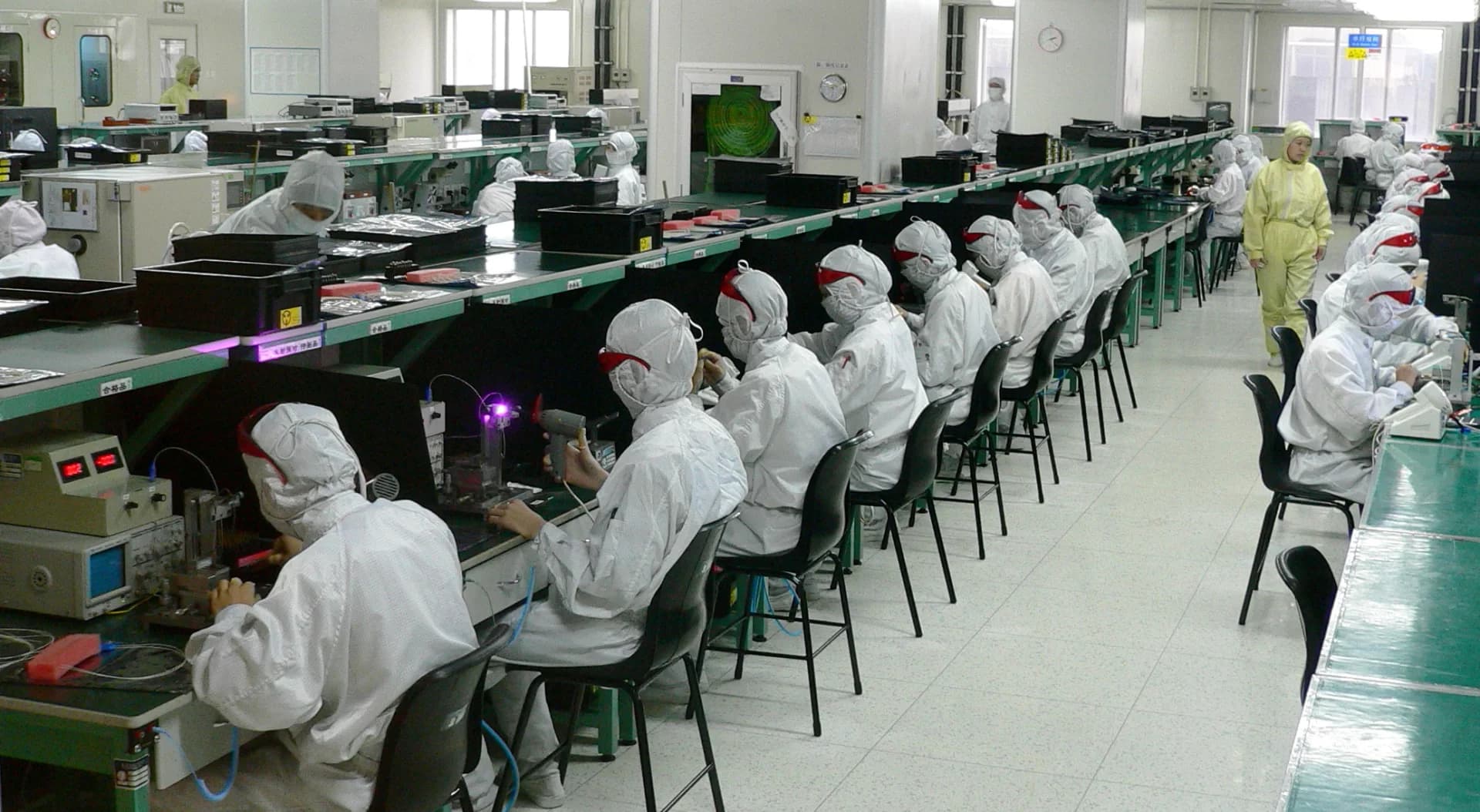 Large electronics assembly factory with cleanroom operators working at parallel production lines