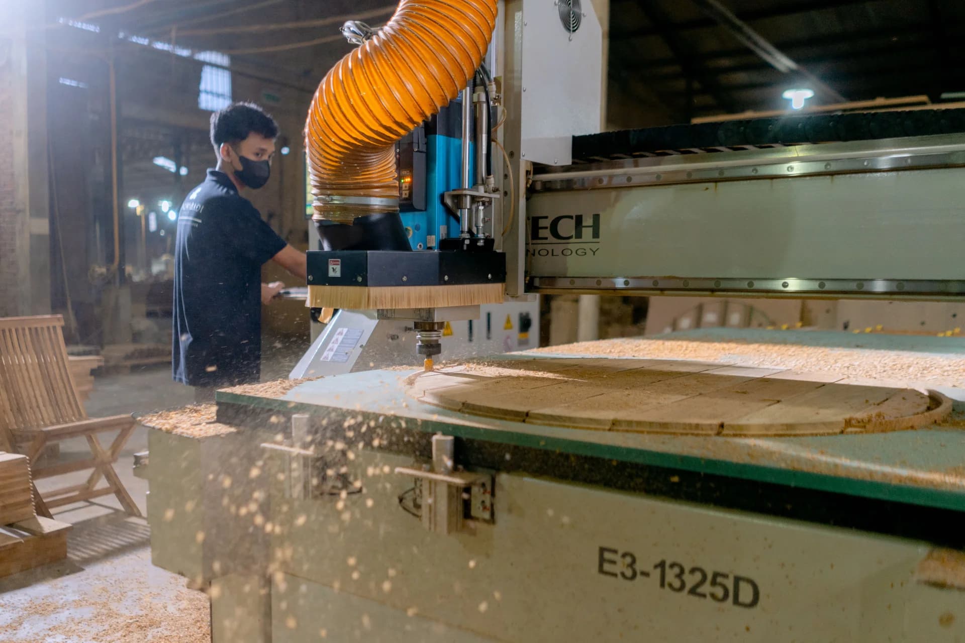 Operator using a large CNC woodworking machine on a furniture factory floor