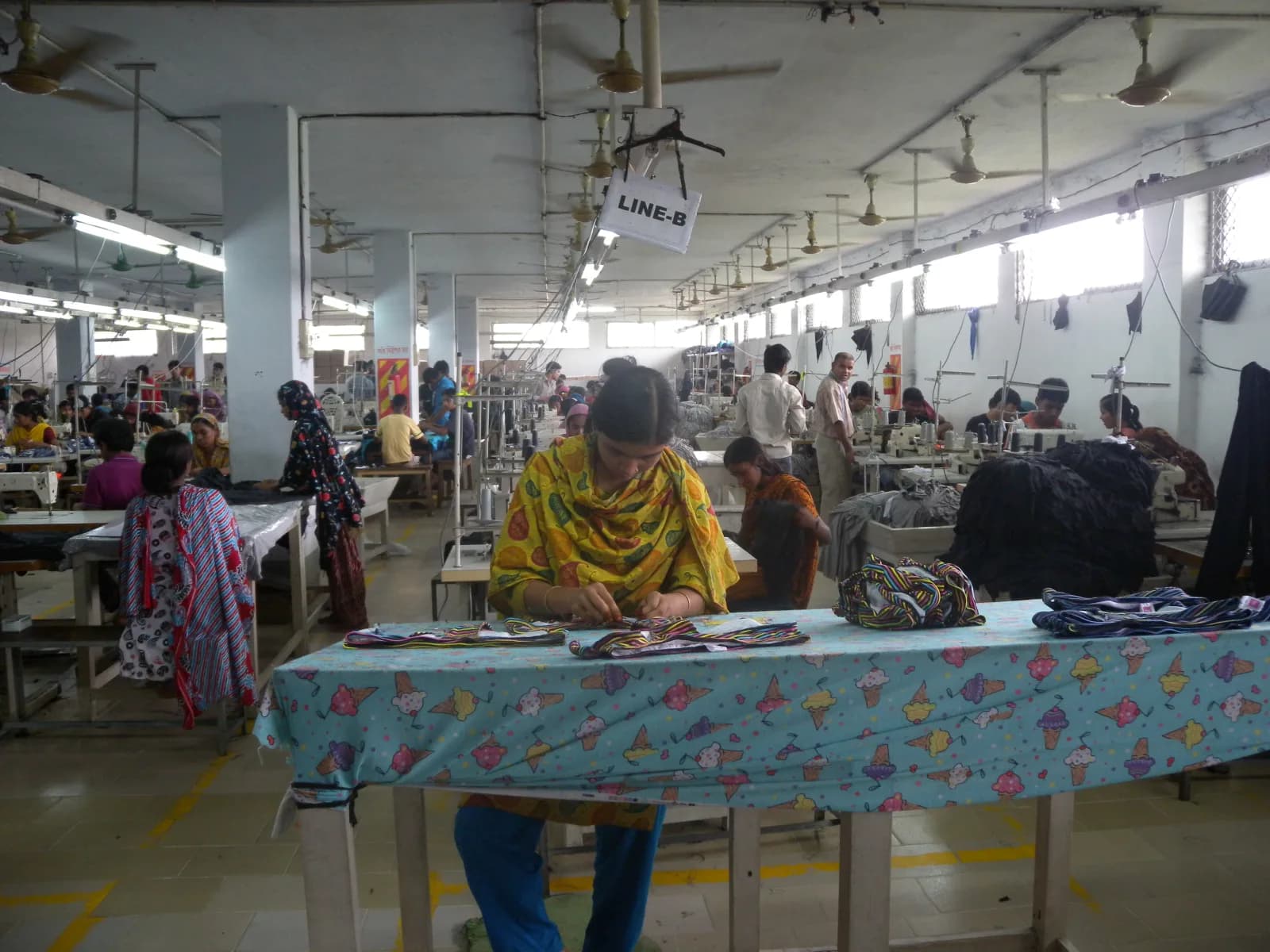 Garment production floor with sewing lines and workers handling clothing pieces
