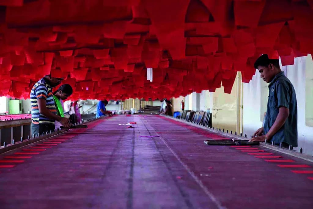 Workers handling fabric across a long production table in India