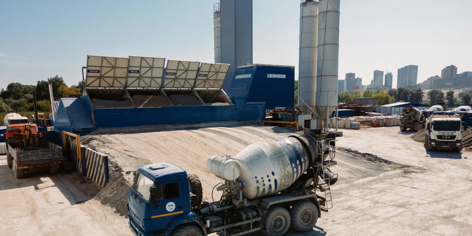 Ready mix concrete batching plant with aggregate bins, cement silos and transit mixer trucks
